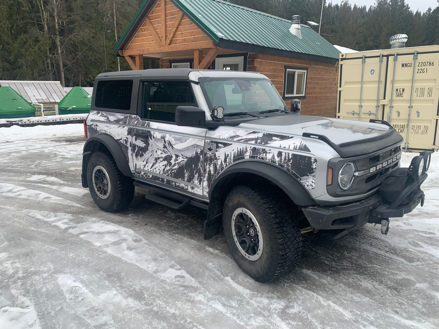 Ford Bronco 2D with MEK removable trail armor featuring a black and white mountain design, parked on icy terrain.